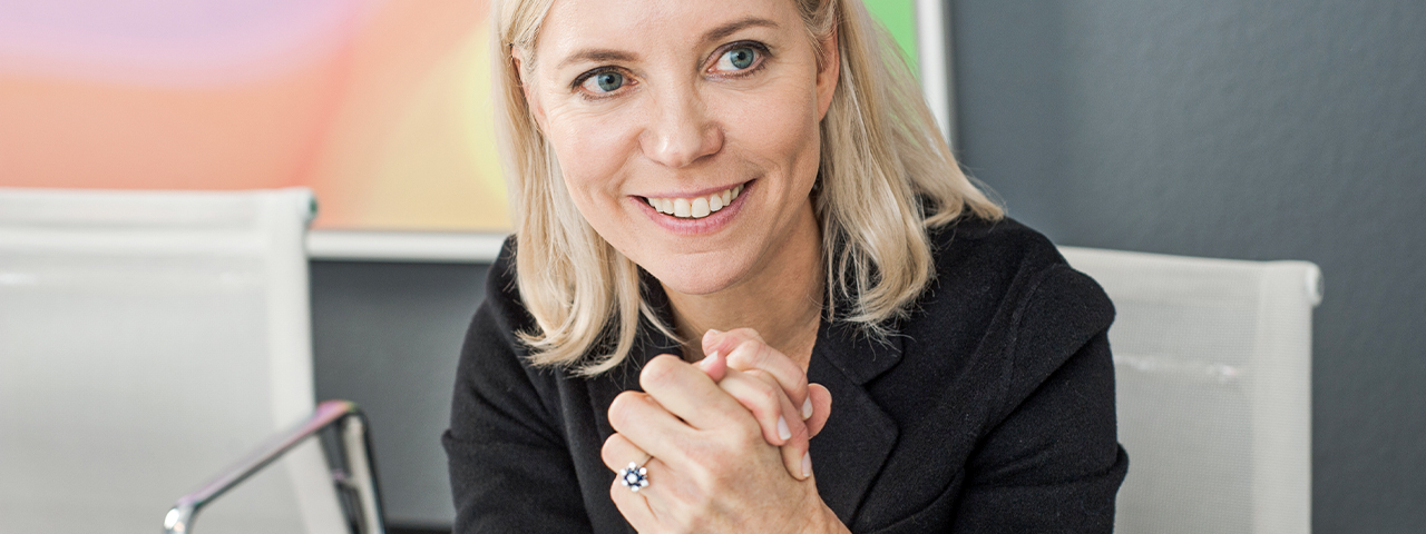 Eine Frau blickt lächelnd zur Seite. Ihre Handflächen liegen aufeinander.